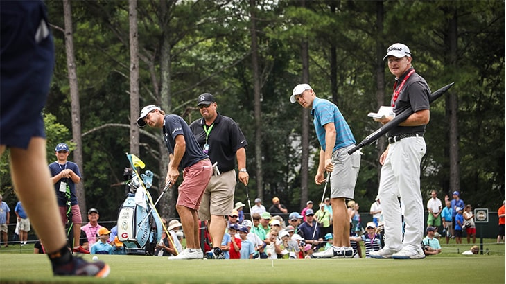 Kisner and Spieth watch their putts roll on the...